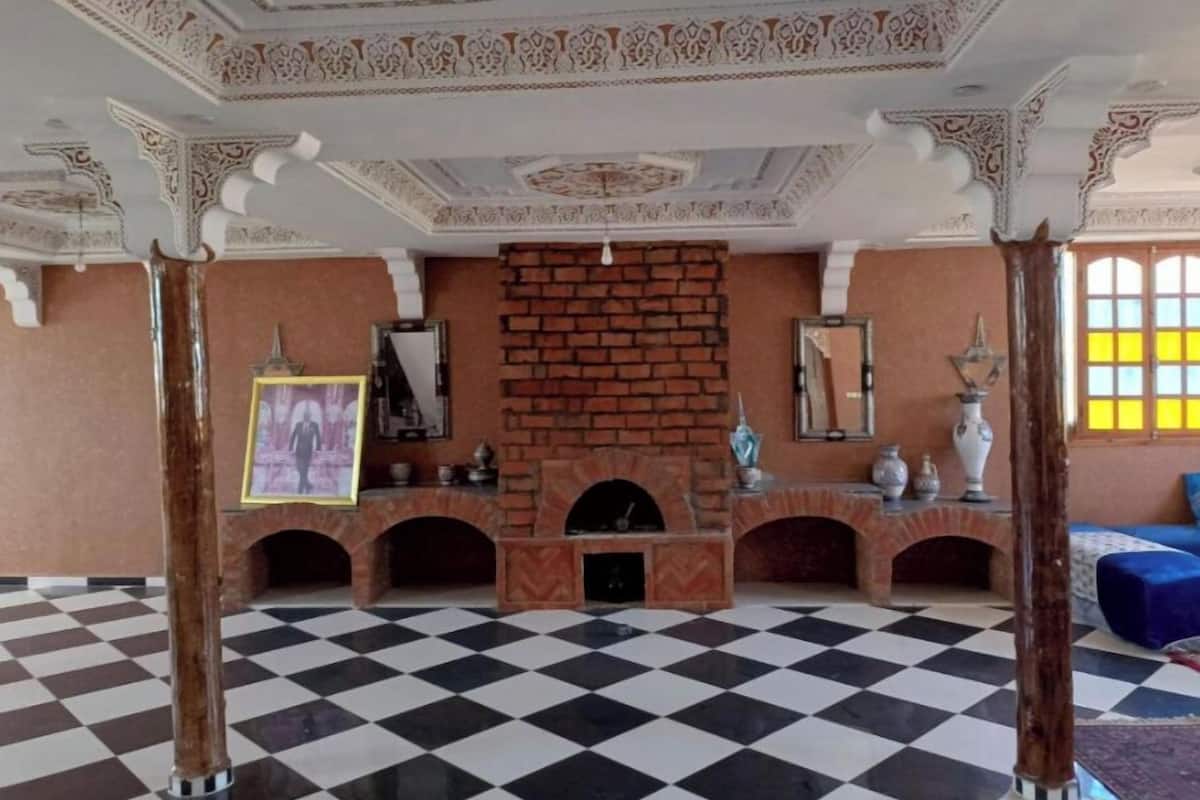 A lobby with a checkered floor, a brick fireplace, and ornate ceiling decorations.