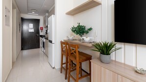 Eine moderne Küche mit Essbereich, einem an der Wand befestigten Fernseher und einem Blumentopf auf der Arbeitsplatte.