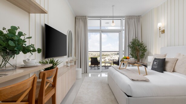 Ein modernes Hotelzimmer mit Flachbildfernseher, einer Essecke mit Holzsesseln, einer Couch und einem Balkon mit Blick.