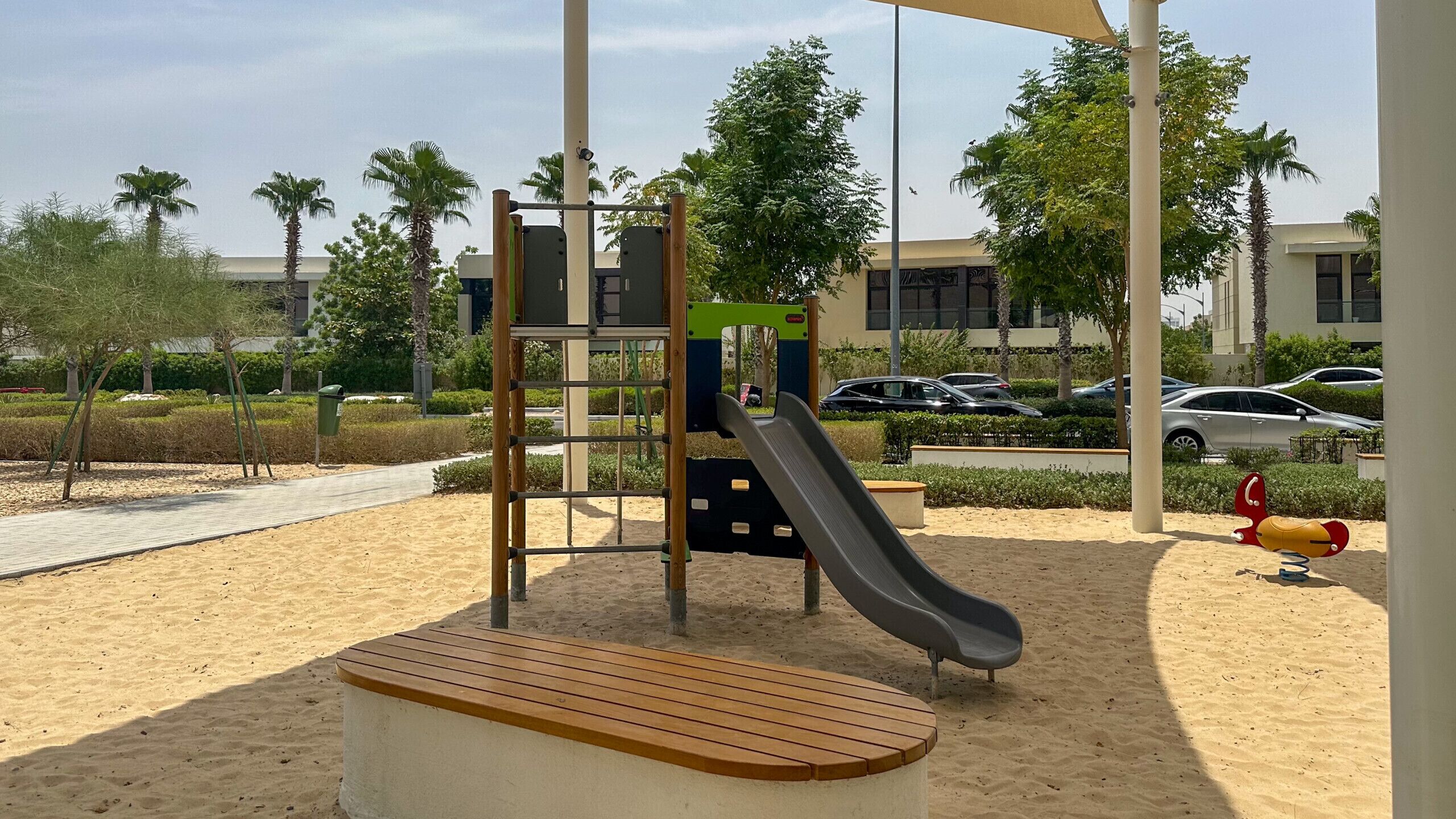A playground with a slide, climbing structure, and a bench.