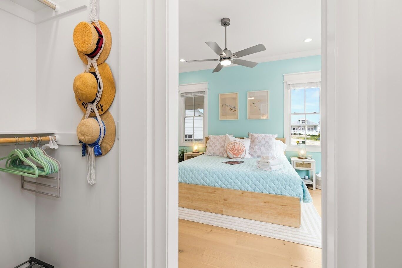 A bedroom with a bed, a ceiling fan, and a view of the outside.