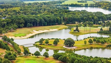 An aerial view of a golf course with multiple ponds, sand bunkers, and a bridge.
