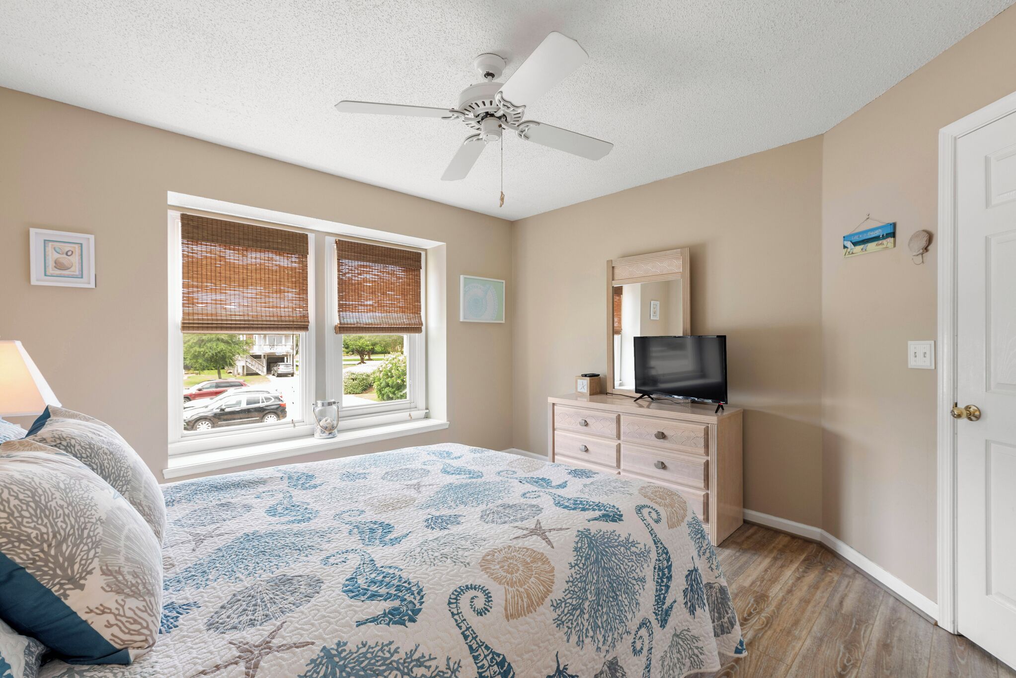 A bedroom with a bed, a dresser, a television, and a window with blinds.