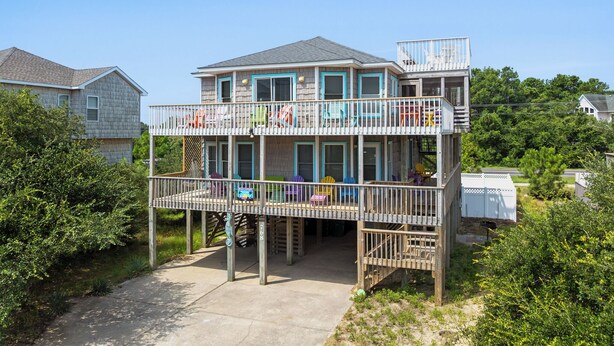 A two-story house with a balcony and a deck area. - Beach Therapy: Private Heated Pool and Hot Tub (Corolla)