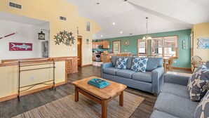 A spacious living room with a sofa, coffee table, and a dining area with chairs and a table. - Beach Therapy: Private Heated Pool and Hot Tub (Corolla)