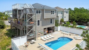 A two-story house with a wooden deck, a swimming pool, and a fenced backyard. - Beach Therapy: Private Heated Pool and Hot Tub (Corolla)
