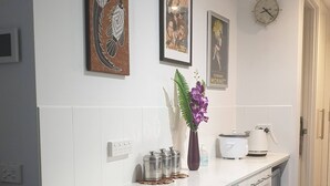 A modern kitchen with white cabinetry, a white countertop, and a clock on the wall. - Amazing City Views on 18th Floor With car Park (Melbourne)