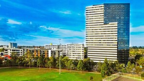 Ein modernes Stadtgebiet mit einem markanten Hochhaus, umgeben von kleineren Gebäuden und Grünflächen.