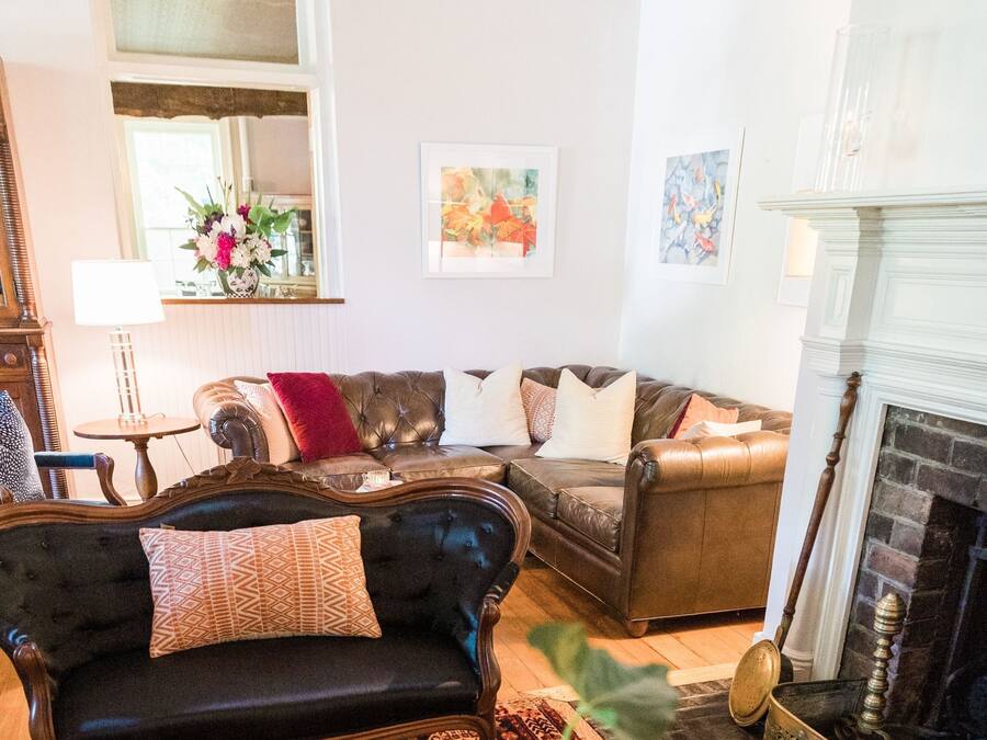A living room with a leather sofa, a patterned rug, and a fireplace.