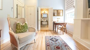 Amplia sala de estar con un sillón grande, comedor con mesa y sillas, y vista a la cocina por una puerta abierta.