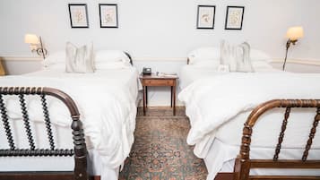 Een hotelkamer met twee bedden, een nachtkastje, een lamp en een kunstwerk in een lijst aan de muur.