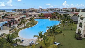 Ein Resort mit einem großen Schwimmbad, umgeben von Palmen und Liegestühlen.