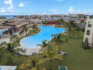 Ett semesterhotell med en stor pool omgiven av palmer och solstolar.