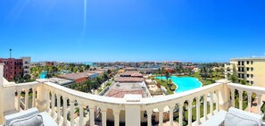 Um resort com várias piscinas, céu azul límpido e vista para o oceano.