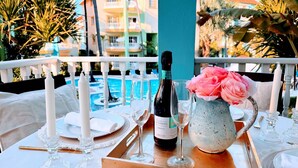 A table set for two with a bottle of wine, a pitcher, and a vase of flowers. - Walk to Beach, Shops, Dining, Pool View, Fast Wifi (Punta Cana)