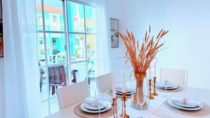 A dining table set with white plates, glasses, and a vase with tall, thin plants. - Walk to Beach, Shops, Dining, Pool View, Fast Wifi (Punta Cana)