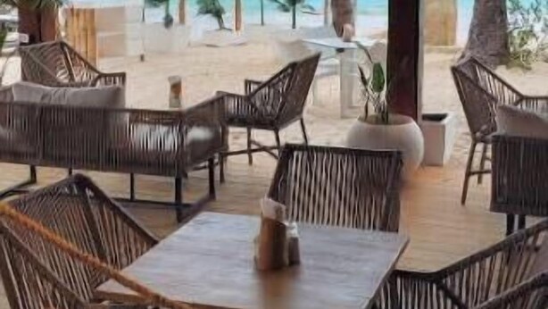An outdoor seating area with wicker furniture and a view of the ocean. - Walk to Beach, Shops, Dining, Pool View, Fast Wifi (Punta Cana)