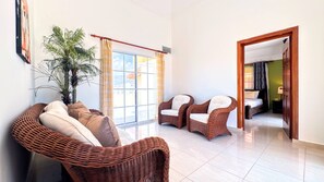 A spacious living area with wicker furniture, a large window, and a view of the city.
