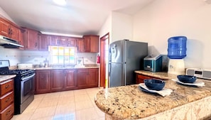 A kitchen with wooden cabinets, a stainless steel refrigerator, a water dispenser, and a microwave.