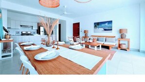 Een moderne keuken met witte kasten, een houten eettafel gedekt met borden en een hangende lamp.