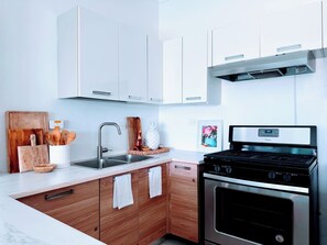 A modern kitchen with white cabinets, a stainless steel stove, and a wooden countertop.