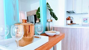A kitchen with a white countertop, copper pots, a white bowl, and a plant.