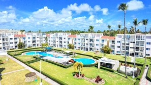 Un hotel de varios pisos, con zona de piscina central y vegetación circundante.