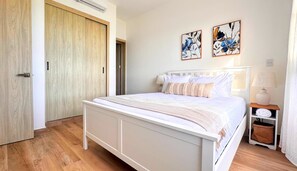A bedroom with a bed, a bedside table, a lamp, and two wall-mounted paintings.