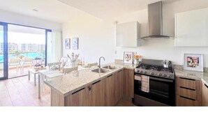 Een moderne keuken met een gasfornuis, een roestvrijstalen spoelbak en houten kastjes.
