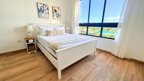 A bedroom with a bed, bedside tables, and a large window with a view.