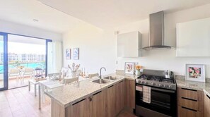 A modern kitchen with a gas stove, stainless steel sink, and wooden cabinets.
