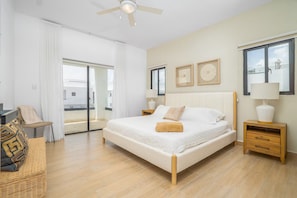 A bedroom with a bed, bedside tables, a chair, and a view through a glass door.