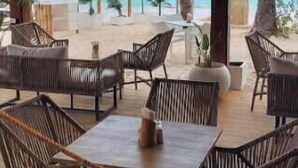 An outdoor seating area with wicker furniture and a view of the ocean.