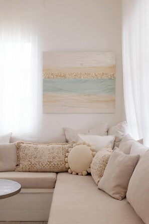 Ein Wohnzimmer mit einem beigefarbenen Ecksofa, einem runden Couchtisch und einem an der Wand hängenden Gemälde.