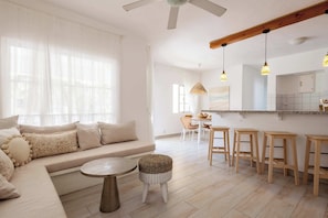 Ein modernes Wohnzimmer mit einer Couch, einem runden Tisch und einer Essecke mit Hocker.