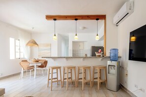 A modern kitchen with a wooden ceiling, bar stools, a water dispenser, and a large mirror. - Steps 2 Beach w Loungers, Pool-view, Priv Rooftop (Punta Cana)