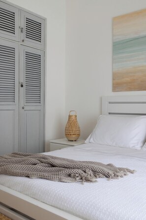 A bedroom with a bed, a nightstand, a wall-mounted lamp, and a wardrobe. - Steps 2 Beach w Loungers, Pool-view, Priv Rooftop (Punta Cana)