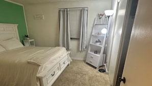 A bedroom with a bed, a nightstand, a dresser, a window with curtains, a door, and a lamp. - Location location location ! (Lakewood)