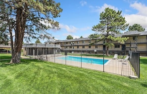 A motel with a swimming pool, fenced yard, and multiple-story buildings.