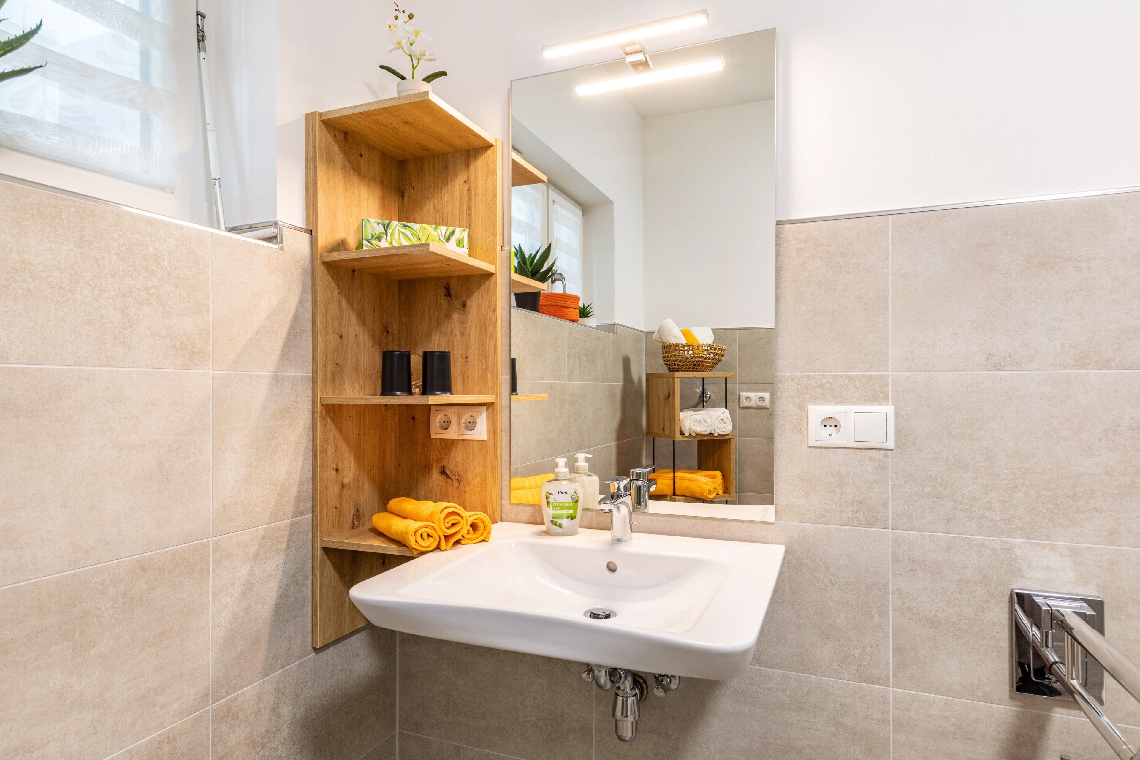 Ein Badezimmer mit Waschbecken, Holzregalen und einem Spiegel.