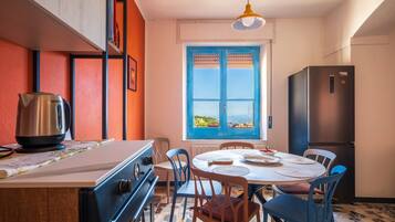 Une cuisine équipée d’une cuisinière, d’une bouilloire et d’une table à manger avec des chaises.