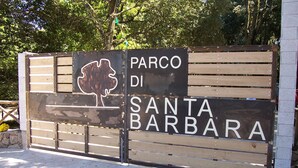 Une porte en bois sur laquelle est apposée une plaque indiquant : « Parco di Santa Barbara ».