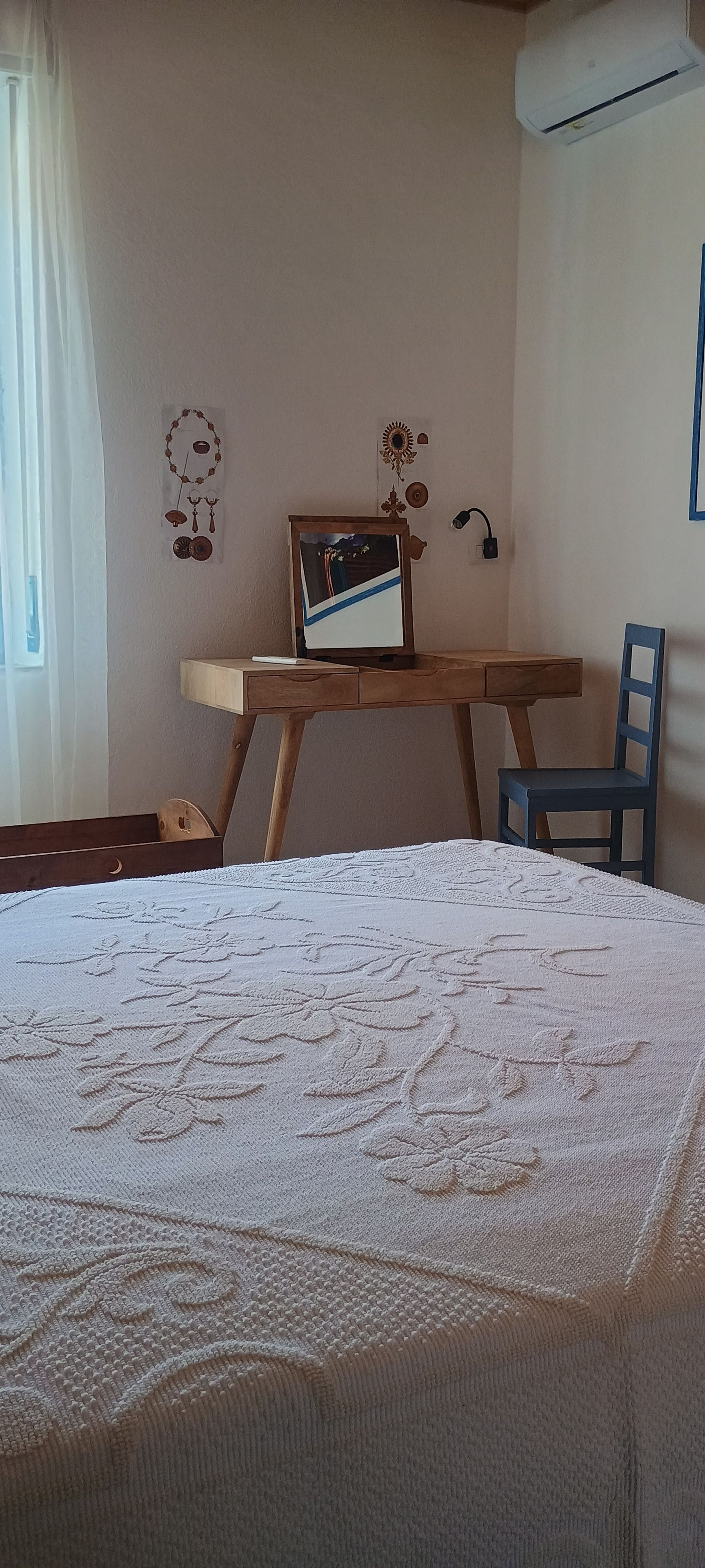 Een slaapkamer met een bed, een bureau, een stoel en een wandairconditioner.