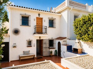 Un bâtiment à deux étages doté d’un balcon, d’un banc et d’un petit jardin agrémenté de galets.