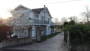 A two-story house with a balcony, a gated driveway, and a garden. - Hotel Il Ciliegio (Santo Stefano del Sole)