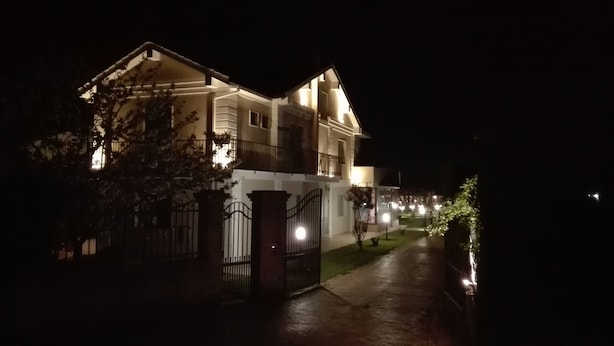 A two-story house with a gated entrance, a visible balcony, and a well-lit pathway. - Hotel Il Ciliegio (Santo Stefano del Sole)
