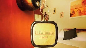 A keychain with "Il Ciliegio Hotel" text, a bed, and a painting on the wall. - Hotel Il Ciliegio (Santo Stefano del Sole)