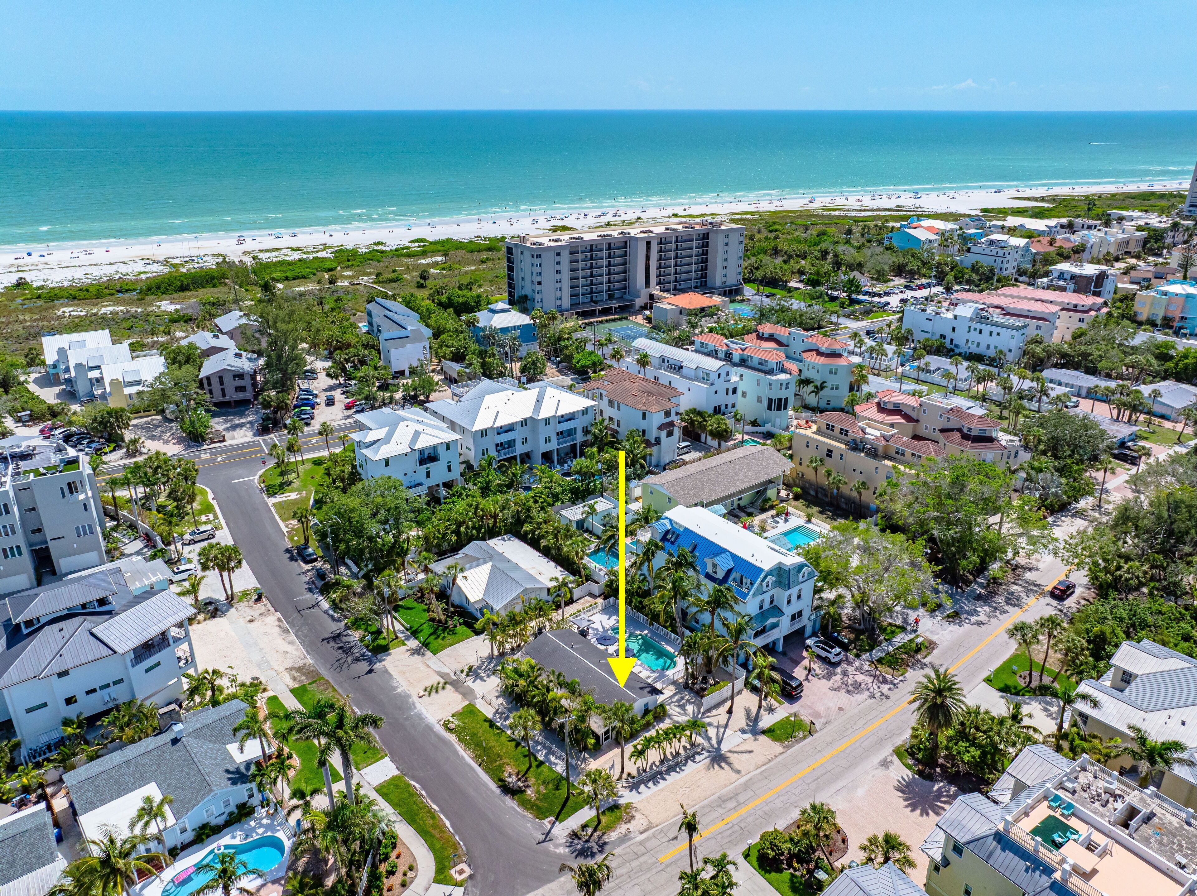 Vista aérea de uma área residencial costeira com edifícios, estradas e uma praia.