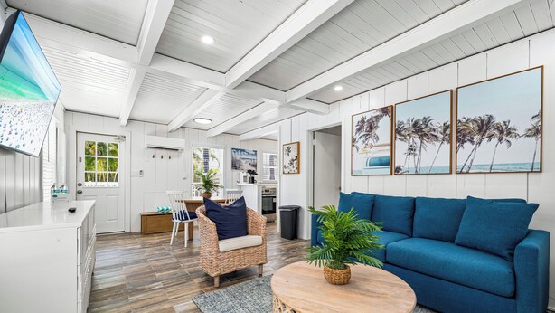 A modern living room with a blue sofa, wicker chair, and a round wooden coffee table. - Cozy Cottage Near Siesta Key Village! (Siesta Key)