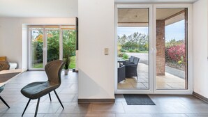 A modern interior with a dining area, a sliding glass door leading to an outdoor patio, and a potted plant. - Holiday Home 'Großes Im Grünen -' with Private Terrace, Private Garden and Wi-Fi (Dummerstorf)